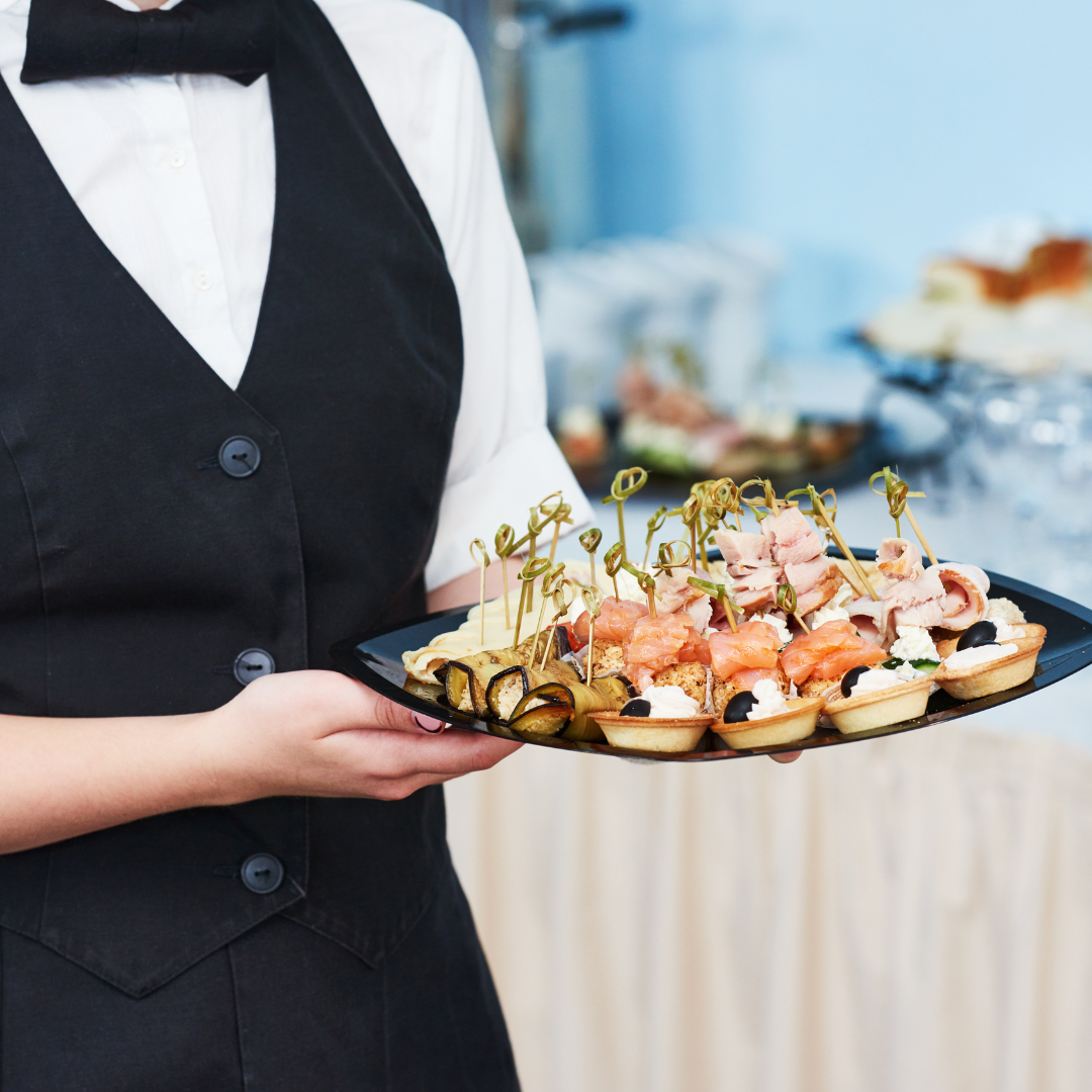 Ein Kellner serviert ein Tablett mit Fingerfood-Snacks zur Auflockerung beim Sektempfang auf einer Hochzeit.
